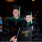 Shane Speights and Amanda Deel stand together in graduation attire with diplomas.